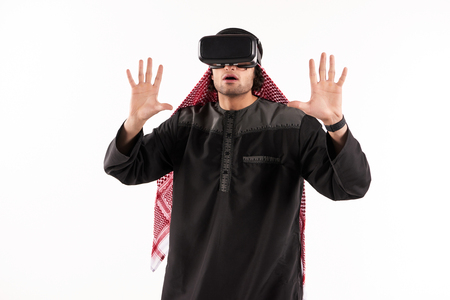 Arab man in virtual reality glasses plays interactive game. Future technology concept. Isolated on white background.の写真素材
