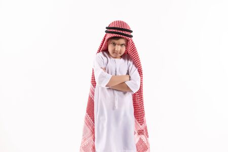 Arab discontented boy in keffiyeh stands with arms crossed. Isolated on white background. Studio portrait.の写真素材