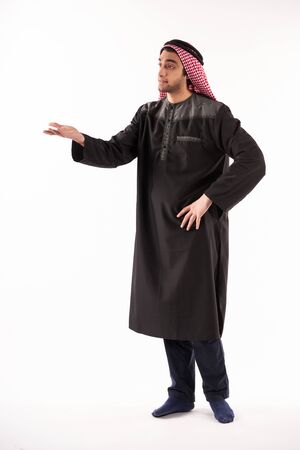 Arab indignant man in keffiyeh stands with arm outstretched. Isolated on white background. Studio portrait.の写真素材