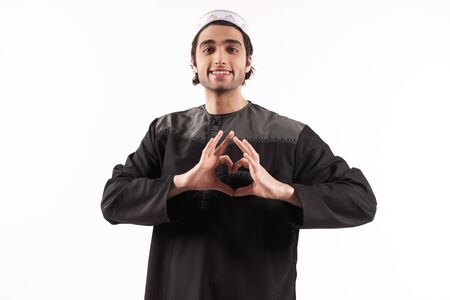 Arab man in national clothes shows heart gesture. Isolated on white background. Studio portrait.の写真素材