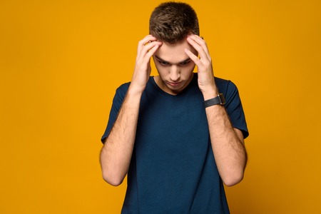 Young handsome thin guy in confusion isolated on yellow background. Studio portrait. Male emotions.の写真素材