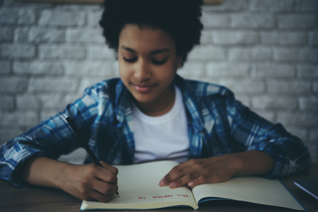 African American little preschooler doing homework sitting at table. Child education concept.