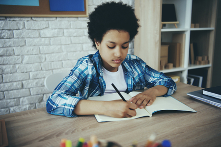 African American little preschooler doing homework sitting at table. Child education concept.