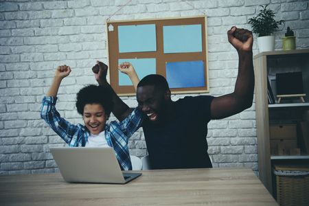 African American father and son are happy to raise hands up. Learning to work with computer. Child education concept.の写真素材