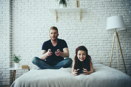 Happy single father and teen daughter with joysticks playing video game. Family leisure concept....