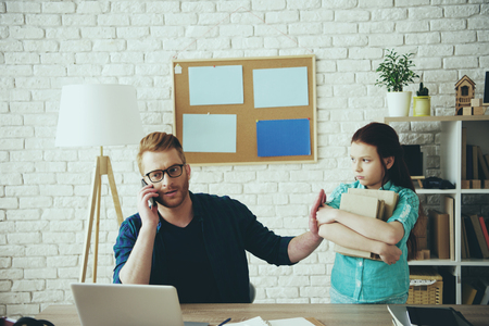 Busy young father refuses to help daughter to do homework at home. Child education concept. Lack of attention. Fatherhood.の写真素材