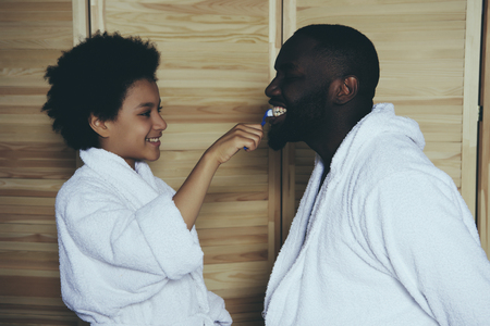 Black father and little son in bathrobes brush teeth in bathroom. Men traditions. Generations. Father Day.の写真素材