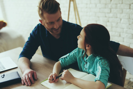 Teen daughter does homework at home with single father. Child education concept. Fatherhood.の写真素材