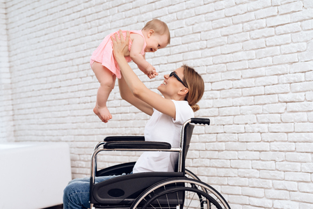Mother in wheelchair play with newborn baby. Disabled, motherhood concept.の写真素材