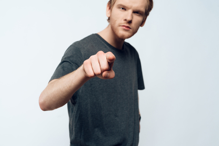 Portrait of Angry Young Man Pointing Forefinger. Ginger Serious Young Guy in Casual Clothes has Imperative Face Expression Isolated on White background. Concept of Human Emotionsの写真素材