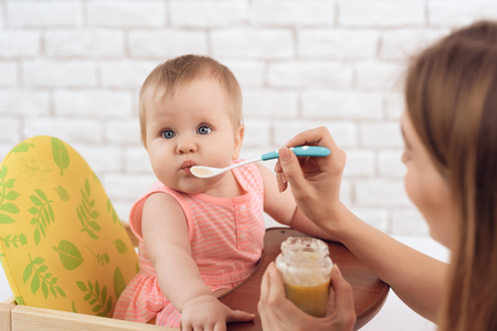 Mother with puree and spoon feeding little baby. Family, motherhood concept.の写真素材