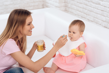Mother with puree and spoon feeding little baby. Family, motherhood concept.の写真素材