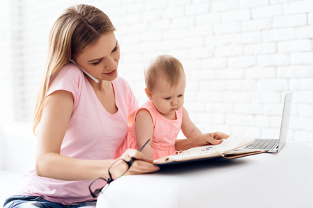 Mother with baby working and using smartphone. Motherhood concept.の写真素材