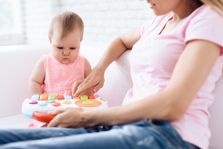 Cute baby playing toy on sofa with mother. Newborn, motherhood concept.の写真素材