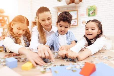 Children put puzzles together with adults. There are a lot of details on the table. They have classes.の写真素材