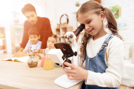 A child is looking through a microscope. The children have a lesson. An adult teacher helps them.の写真素材