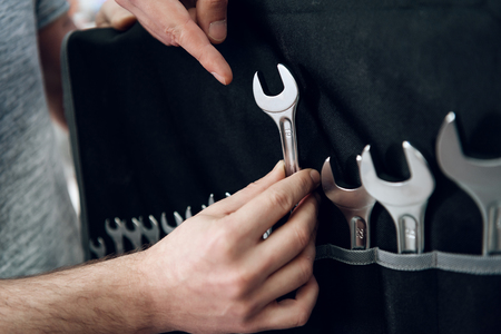 Salesman in checkered shirt is showing bearded client set of wrenches in power tools store.の写真素材