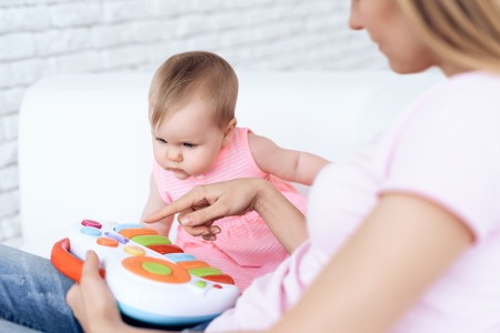 Cute baby playing toy on sofa with mother. Newborn, motherhood concept.の写真素材