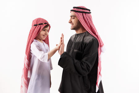 Arab happy father gives five little sons in national attire. Isolated on white background. Parenthood concept.の写真素材