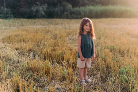 Happy little girl celebrating, holding out her hands in a yellow fieldの写真素材
