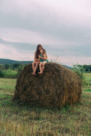two little sisters sit on a haystackの写真素材