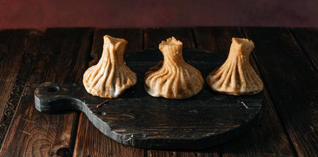 Georgian fried khinkali dumplings with meat on a wooden plank. A traditional dish of Caucasian cuisine.の写真素材