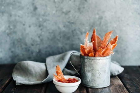 Dried chicken, dried poultry, cut into strips in a metal bucket on a wooden background. Serving a...