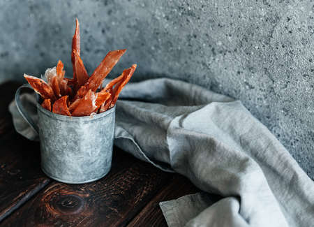 Dried chicken, dried poultry, cut into strips in a metal bucket on a wooden background.の写真素材