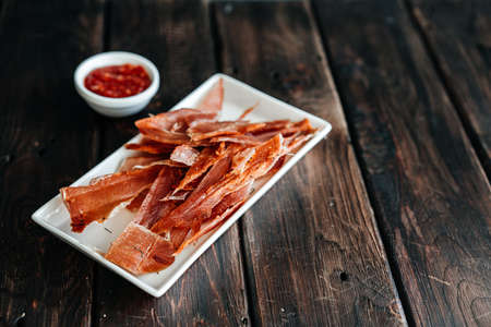 Dried chicken cut into strips on a wooden board with salt, pepper, adjiga, ketchupの写真素材