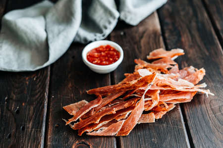 Dried chicken cut into strips on a wooden board with salt, pepper, adjiga, ketchupの写真素材