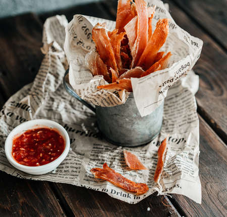 Dried chicken, dried poultry, cut into strips in a metal bucket on a wooden background. Serving a meal in a restaurantの写真素材