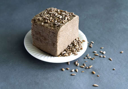 halva from sunflower seeds on a white plate with seeds, on a gray background. National traditional Turkish halva . High quality photoの写真素材
