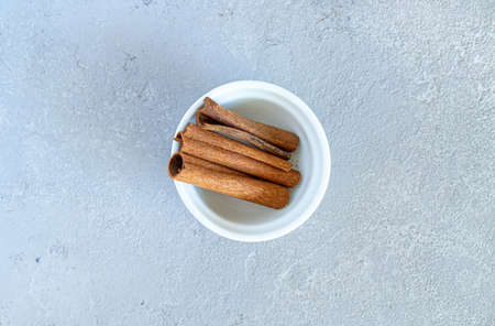 cinnamon sticks on a white plate, on a gray backgroundの写真素材