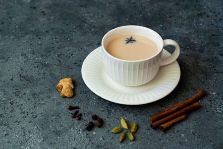 Indian tea masala chai. Seasoned chai masala tea with milk and spices on a dark gray background.の写真素材