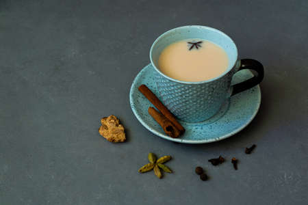 Indian tea masala chai. Seasoned chai masala tea with milk and spices on a dark gray background.の写真素材