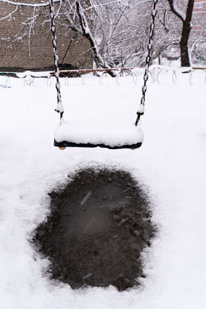 Snow covers the seats of a swing set after a storm. high quality photoの写真素材
