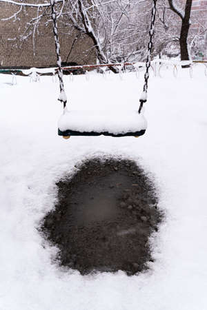 Snow covers the seats of a swing set after a storm. high quality photoの写真素材