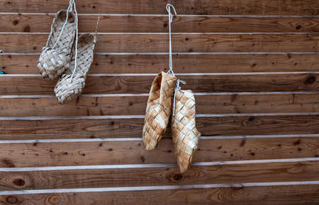 Birchen woven bast shoes hang on a log wall. high quality photoの写真素材