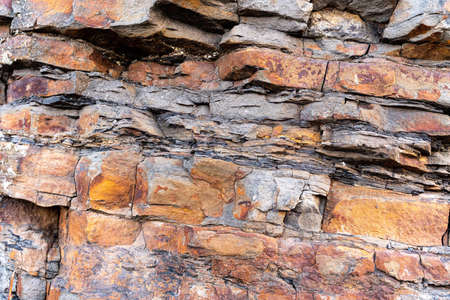 Closeup of dark dged shabby cliff cracks. Gray stone rock texture of mountains. Concept of geology and mountaineering. high quality photoの写真素材