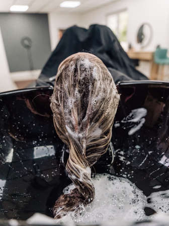 A woman washes her hair with shampoo. beauty saloon. hair wash. high quality photoの写真素材