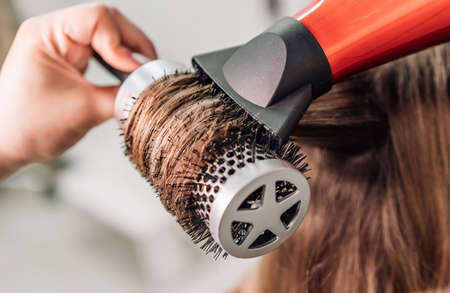 Drying blonde hair with a hair dryer and a round brush. high quality photoの写真素材