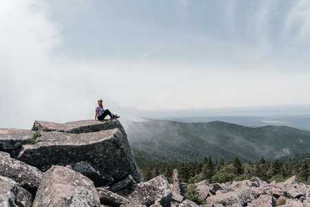 A girl on top of Mount Pidan looks at a beautiful mountain valley in the fog in summer. Travel and tourism. Hiking High quality photoの写真素材