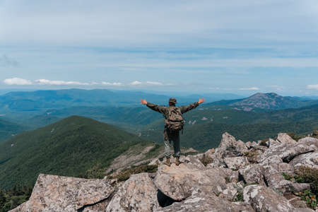 A man stands on top of a mountain and enjoys a beautiful mountain view. Taken on top of Mount Pidan, Russia. high quality photoの写真素材