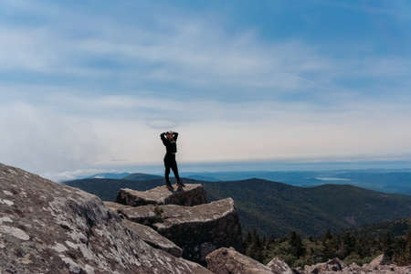 A girl on top of Mount Pidan looks at a beautiful mountain valley in the fog in summer. Travel and tourism. Hikingの写真素材