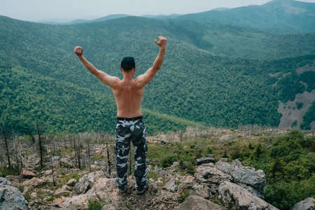 A hiker on top of a mountain enjoys the aerial view while raising his hands above the clouds. Mount Falaza. high quality photoの写真素材