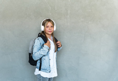 Student life, modern lifestyle and education concept. cheerful pretty female student with headphones and backpack. high quality photoの写真素材