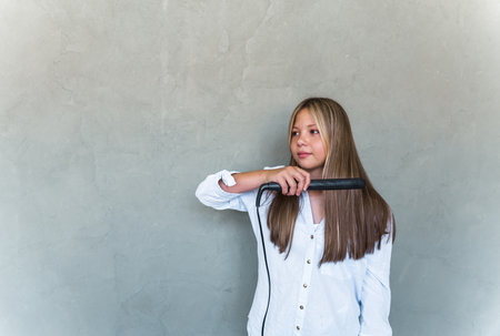 Young beautiful woman straightening her long hair. high quality photoの写真素材
