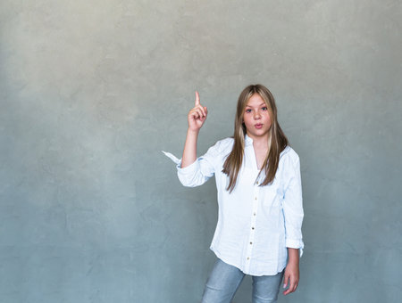 Excited beautiful girl smiling, pointing fingers upper left corner and looking pleased at logo. high quality photoの写真素材
