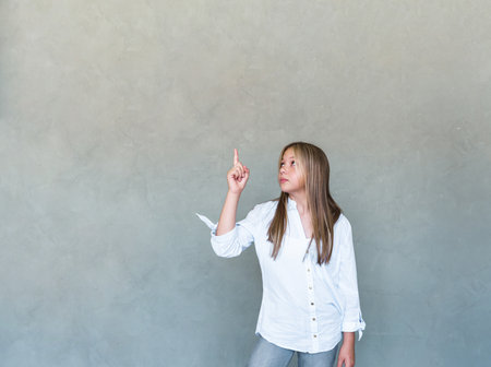 Excited beautiful girl smiling, pointing fingers upper left corner and looking pleased at logo. high quality photoの写真素材