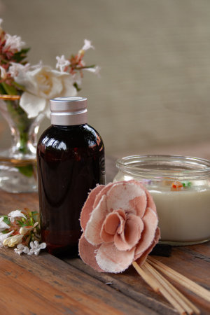 Fragrance diffuser in caramel bottle and mixed natural and fabric flowers on rustic table .Neutral grey backgroundの写真素材
